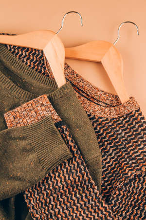 Sweaters on beige background - vertical image. Clothing donations, conscious and environmentally friendly consupmtion - new trends in shopping. Slow fashion concept. Selective focusの写真素材