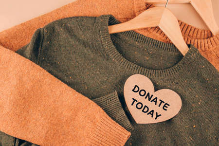 Clothing donations, conscious and environmentally friendly consupmtion - new trends in shopping. Christmas donations concept. Sweaters on beige background with copyspace. Selective focusの写真素材