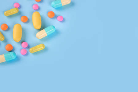 Assorted medicine pills, capsules and tablets on blue background with copyspace. Immune system vitamins and supplemets. Selective focusの写真素材