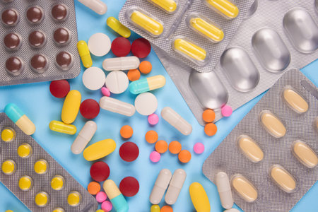Assorted multicolored medicine pills, capsules and tablets in blisters on blue background. Immune...