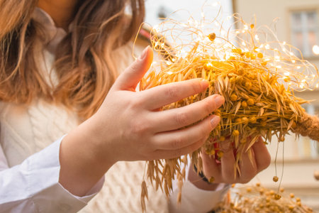 Young woman holding Didukh as a Ukrainian Christmas symbol on souvenir market - sheaf of wheat used for celebrating Christmas in Ukraine. Ancient traditions concept. Close upの写真素材