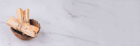 Banner with Palo Santo tree sticks inside coconut shell on light marble table background - holy incense tree from Latin America. Meditation, mental health or personal fulfilment conceptの写真素材