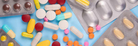Banner - assorted multicolored medicine pills, capsules and tablets in blisters on blue background. Immune system vitamins and supplemets. Dietary bio supplements. Selective focusの写真素材