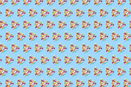 Pattern made of assorted multicolored medicine pills, capsules and tablets in heart shapeImmune system vitamins and supplemets. Dietary bio supplements on blue background. Cardiovascular deseases.の写真素材