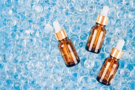 Mock up dropper bottles of facial anti aging serum with collagen and peptides on blue gel bubbles background with copy space. Cosmetic fluid collagen or essential oil. Skin care beauty routineの写真素材