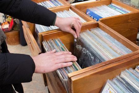 Lviv, Ukraine - March 7, 2021 : a man buying vintage vinyl records on flea market or garage sale....