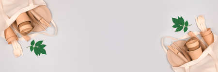 Banner with eco-friendly tableware - kraft paper cups and containers, paper plates and drinking straws in white cotton bag on gray background with copy space. Street food sustainable paper packagingの写真素材