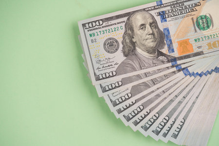 Stack of one hundred dollars banknotes on light green background with copy space. Cash money....