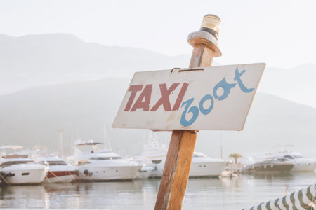 Taxi boat signboard in marina with defocused sailboats as background. Tourist attraction and sea tourist transport. Sea walks during summer vacations in Montenegro, Italy, Spain, Croatia and Franceの写真素材