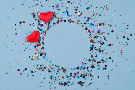 Valentine's day festive composition background. Wreath made of red hearts with multicolored confetti...