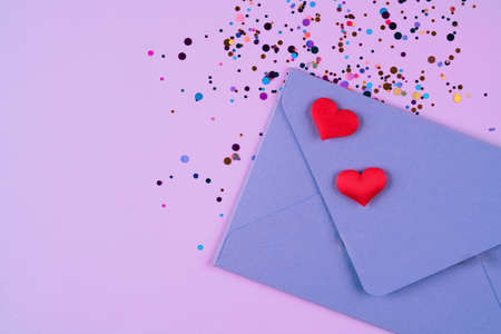 Valentine's day festive background. Purple envelope with red hearts and confetti around on pink background with copy space. Flat lay, top view. Greeting card, invitationの写真素材