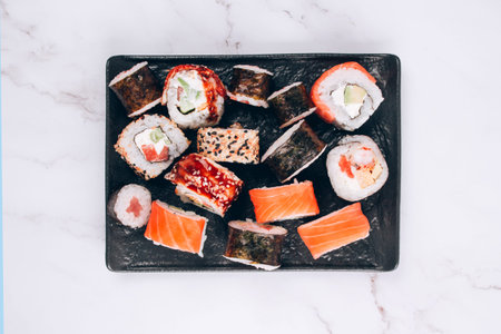 Sushi bar lunch menu - top view on different sushi rolls with salmon, avocado and smocked eel on...