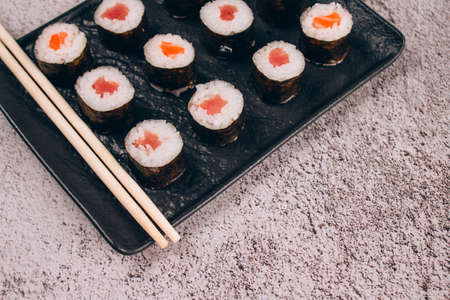 Classic sashimi with salmon or tuna fish, soy sauce and chopsticks on concrete table background - maki sushi roll, nori maki. Online home order food delivery concept, sushi bar menu. Takeout foodの写真素材