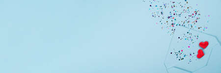 Banner. Valentine's day festive background. Blue envelope with red hearts and multicolored confetti around on pastel blue background with copy space. Flat lay, top view. Greeting card, invitationの写真素材