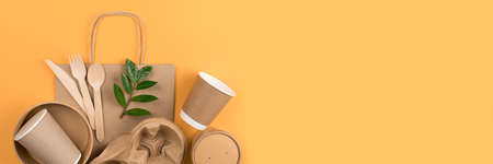 Banner with eco-friendly tableware set. Kraft paper utensils, paper containers and cups, bamboo cutlery on orange background, copy space. Street food paper packaging concept, ethical consumerismの写真素材