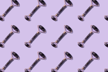 Flat lay pattern with facial massage amethyst gua sha roller on trendy purple background. Face roller, massager made from natural stone, home spaの写真素材