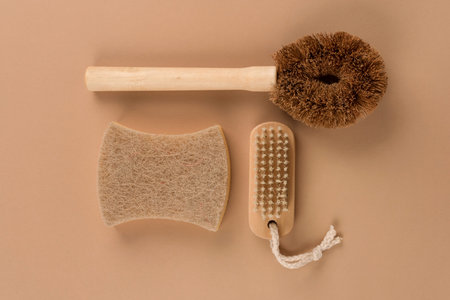 Set of natural household cleaning products - bamboo brushes and organic dishcloth on beige...