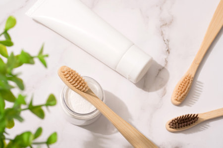 Top view on natural bamboo toothbrushes, mineral toothpowder and toothpaste tube on white table...