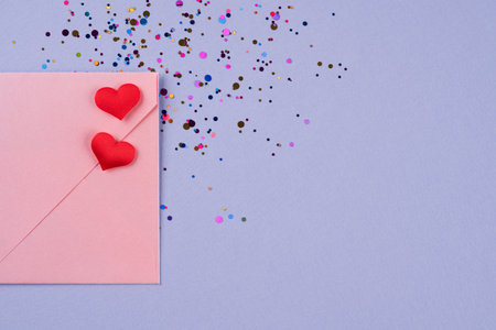 Valentine's day festive background with pink envelope with red hearts and confetti around on trendy...