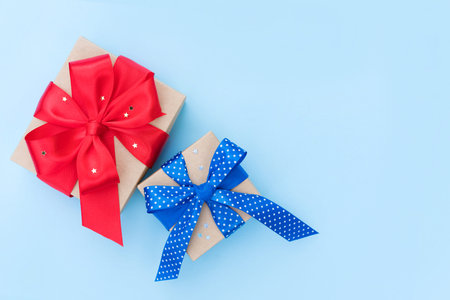 Christmas or birthday present boxes with red and blue ribbon bow on light blue background. Festive...