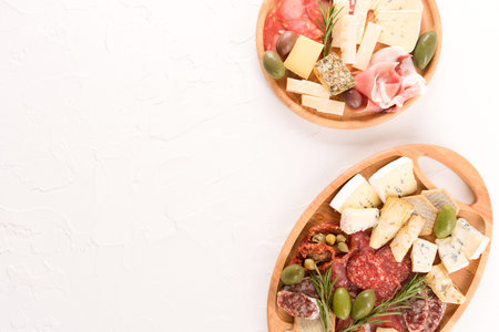 Wooden plates with traditional Italian antipasti - variety of cheeses, sausages served with sun...