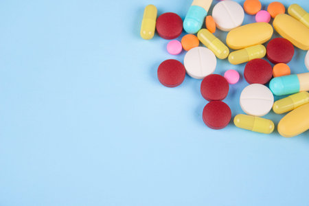 Assorted medicine pills, capsules and tablets on blue background with copy space. Immune system...