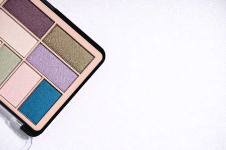 Glitter eyeshadows palette for festive makeup over white holographic background with copy space for text. Professional make up and beauty concept, flat layの写真素材