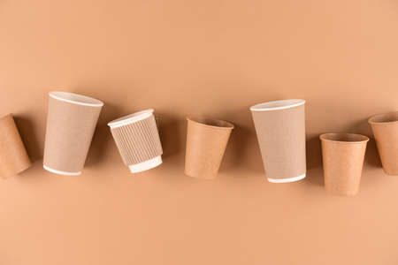 Set of various paper coffee cups over light brown background with copy space. Eco paper cups for hot beverages to go. Sustainable take away food packaging concept. Top viewの素材 [FY310187552029]