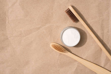 Natural wooden toothbrushes with mineral toothpowder kaolin over kraft paper background with copy space. Natural bath products, organic dentifrice. Mockup image, flat layの写真素材
