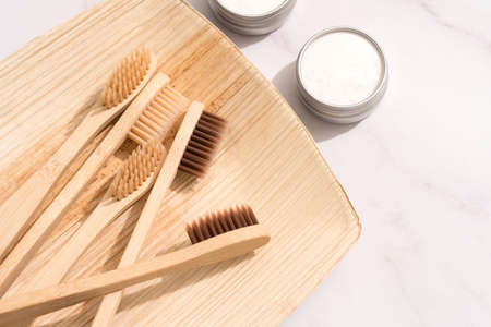 Bamboo toothbrushes and mineral toothpowder, kaolin in aluminium containers over white table background. Natural bath products, organic dentifrice. Mockup image. Top viewの写真素材