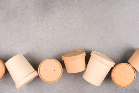 Sustainable food packaging concept. Different disposable kraft paper food containers for food to go with paper cap over gray concrete table background with copy space, mockup imageの写真素材