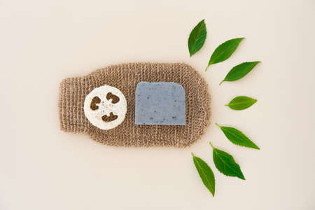Natural bath accessories for skin care - hemp or ramie bath gloves, loofah sponge and handmade soap over light background with copy space. Eco living concept. Flat lay styleの写真素材