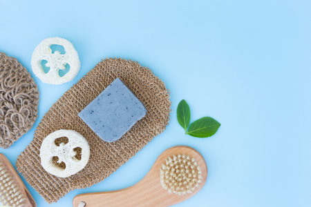 Natural bath accessories for body care and scrubbing over blue background - wooden brush, body...