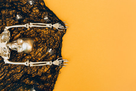 Halloween background with black cobweb, golden spiders and golden skeleton over orange background with copy space for your Halloween project. Invitation templateの写真素材