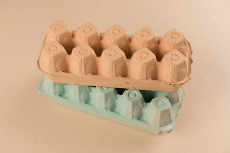 Pulp egg cartons made with pulp and natural straw over light brown background. Eco friendly egg...