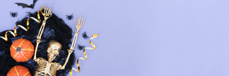 Halloween banner background with many Halloween decorations. Golden skeleton, cobweb, orange pumpkins, bats and spiders over purple background with copy space. Halloween celebration conceptの写真素材