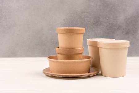 Paper utensils - variety of paper food containers and paper plates against gray wall background with copy space. Sustainable food packaging. Eco paper tablewareの写真素材