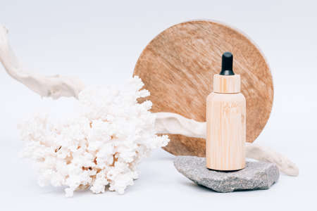 Cosmetic oil with natural Dead Sea minerals in wooden dropper bottle against white background with sea corals and wooden decorations. Algae oil or sea minerals based cosmetics products for skin careの写真素材