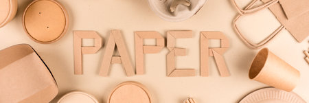 Paper utensils over light brown background with word PAPER made with origami paper letters. Street food sustainable paper packaging, zero waste. Eco- friendly paper tableware. Horizontal bannerの写真素材