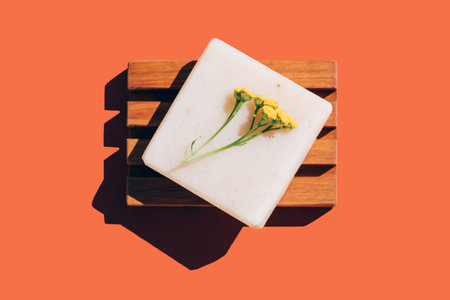 Making herbal soap with natural ingredients at home. Handmade vegan soap bar with flowers over...