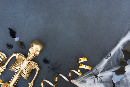 Halloween composition with cobweb, spiders, bats and golden skeleton over dark gray concrete background with copy space. Party invitation templateの写真素材