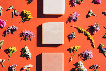 Handmade organic soap bars made with natural ingredients, flowers and herbs over dark orange background. Making herbal soap at home. Top view, flat lay style. Mockupの写真素材