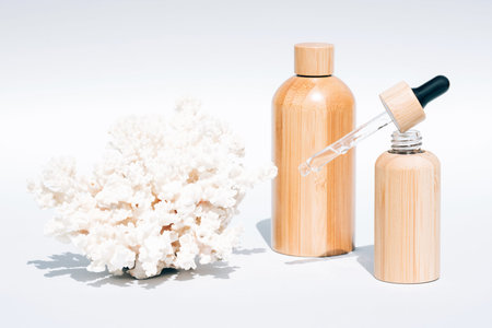 Cosmetic self-care products with natural Dead Sea minerals in refillable wooden bottles against white background with sea corals. Algae oil or sea minerals based beauty products for skin careの写真素材