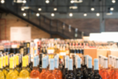 Many blurred bottles with alcohol. Defocused wine bottles background with copy space. Blur liquor...
