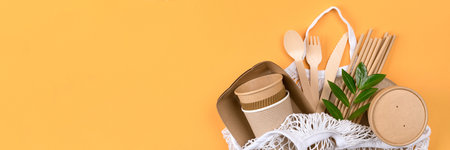 Paper utensils in white cotton bag over orange background. Banner with copy space - sustainable paper food packaging. Street food paper packaging, zero wasteの写真素材
