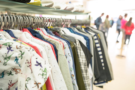 Clothes stall against blurred store background with copy space. Clothes on hangers at thrift store or seconhand storeの写真素材