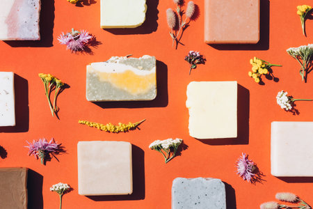 Many handmade organic soap bars made with natural ingredients, flowers and herbs over red brown...