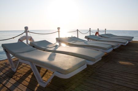 Ten chaise-longues on a wooden pier and sunriseの写真素材