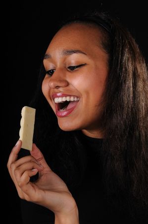 Attractive laughing young woman with white chocolate on black backgroundの写真素材