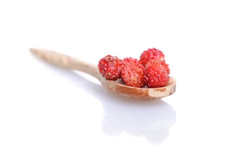 Strawberries in small wooden spoon with soft shadow on white background. Shallow depth of field.の写真素材